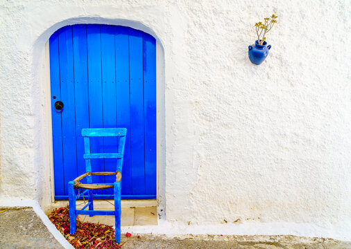 Blue door and chair against white wall Cretan village Crete Greece
