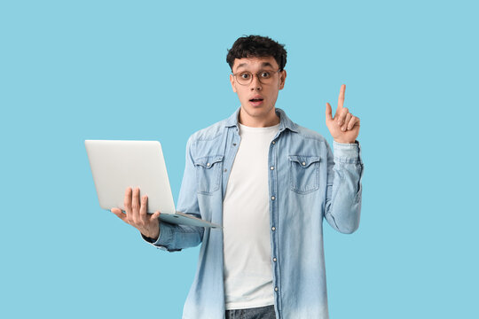 Male screenwriter with laptop pointing at something on blue background
