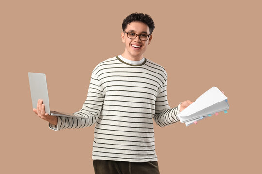 Male screenwriter with scenario and laptop on beige background