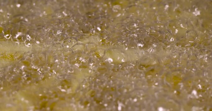 Yellow french fries frying in hot oil, sliced french fries boiling in deep fat frier with a large number of air bubbles, fast food
