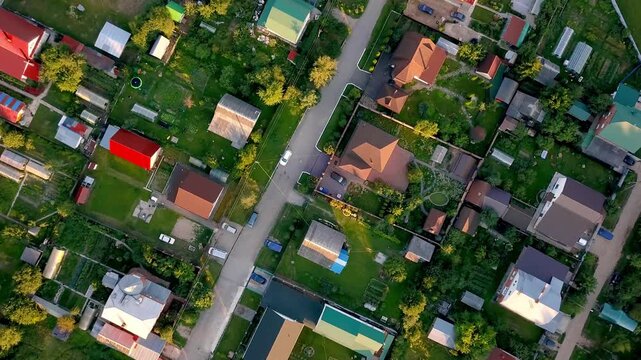 Aerial overhead drone shot of a quiet suburban village with houses, gardens, and streets at sunset