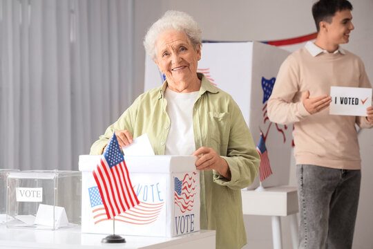 Voting senior woman near ballot box with USA flag at polling station