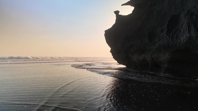 Sunset Horizon Over Ocean Waves and Dark Coastal Cliff