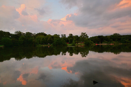 Sunset-iinfused color in the clouds is reflected onto the surface of a lake. The colors provided by the day's fading light were deepened and enhancds by the lake's still, darkened water.