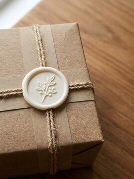 Handcrafted wrapped gift parcel secured with twine string and botanical wax seal stamp