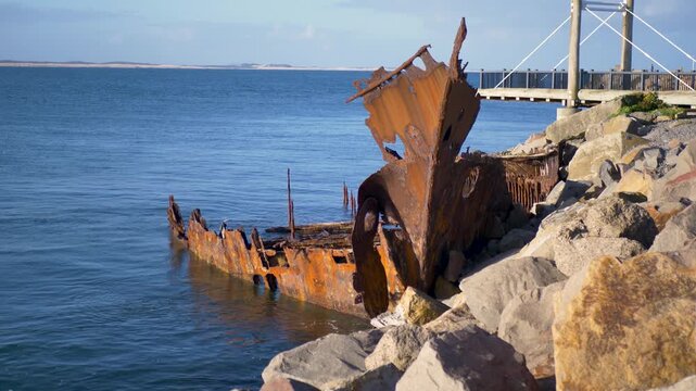 Slow motion landscape of the rusting shipwreck bow and hull remnants landmark at Stockton beach break wall waterfront near Newcastle city harbour foreshore and wharf in Australia history and tourism