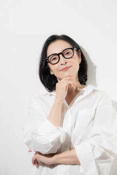 [白背景]眼鏡をかけた50代女性のポートレート、知的で落ち着いた印象のミドル世代とアイウェアのイメージ クローズアップ 　カメラ目線