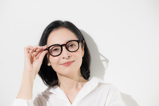 [白背景]眼鏡をかけた50代女性のポートレート、知的で落ち着いた印象のミドル世代とアイウェアのイメージ クローズアップ 　カメラ目線