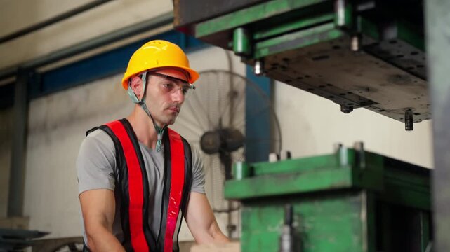 Male industrial worker operating steel cutting machinery during manufacturing production process in metal factory, skilled employee working with heavy industrial equipment in metalworking facility.