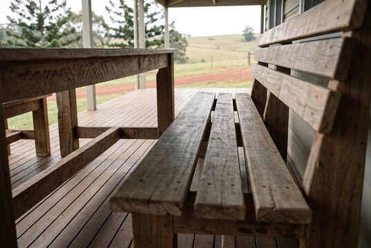 Rustic wooden bench and table on farmhouse veranda facing pasture