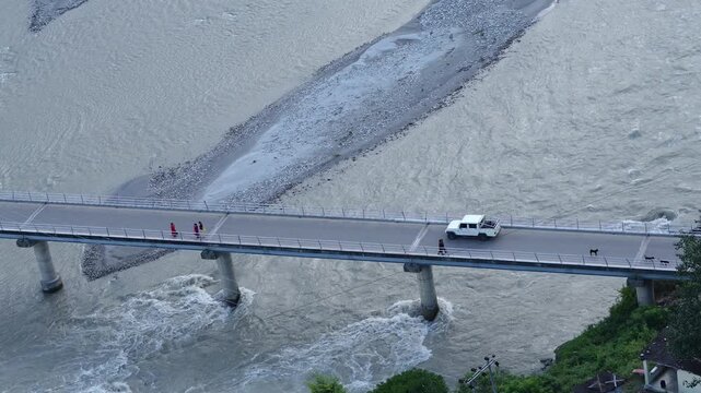 Aerial view of traffic and people crossing a bridge over a rushing river