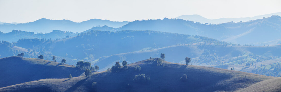Gradients of hills in misty haze, minimalist landscape, panoramic view