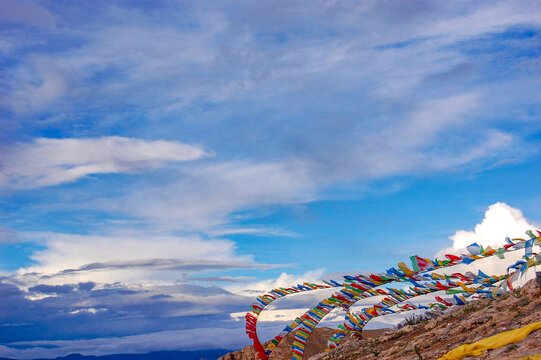 Colorful prayer flags under a blue sky with clouds