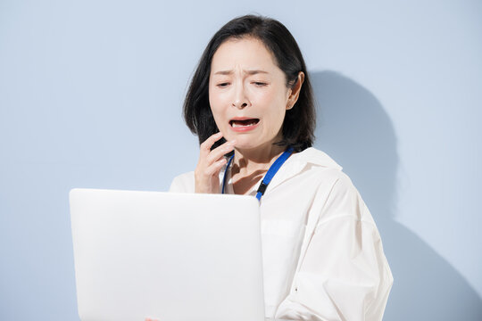 ノートパソコンを見ながら困る表情をする女性会社員、仕事の問題やミス、トラブルやストレスに悩む日本人ビジネスウーマン