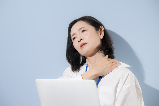 ストレートネックや肩凝りや痛みに悩む女性会社員、ノートパソコン作業による肩こりや疲労を感じる日本人ビジネスウーマン