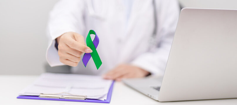 Doctor giving purple and green ribbon to patient for concept of March Anal Cancer Awareness month, Colorectal and Colon Cancer, Healthcare and February world cancer day