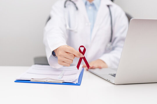 Doctor giving burgundy ribbon to patient for concept of March Multiple Myeloma Cancer Awareness month, September Sickle Cell Anemia, Headache and Migraine week, April Meningitis day
