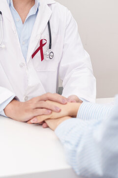 doctor holding patient hand to comfort and support with empathy. burgundy ribbon concept of March Multiple Myeloma Cancer Awareness month, September Sickle Cell Anemia, Headache and Migraine week