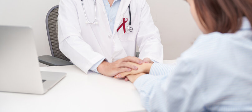 doctor holding patient hand to comfort and support with empathy. burgundy ribbon concept of March Multiple Myeloma Cancer Awareness month, September Sickle Cell Anemia, Headache and Migraine week