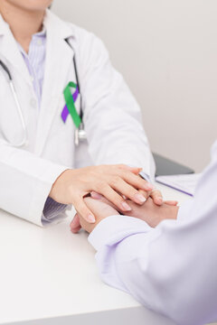 doctor hold patient hand to comfort and support with empathy. purple and green ribbon concept of March Anal Cancer Awareness month, Colorectal and Colon Cancer, Healthcare and February world cancer