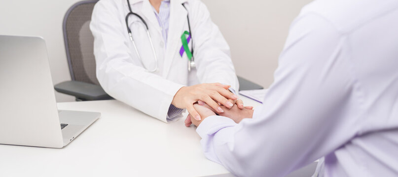 doctor hold patient hand to comfort and support with empathy. purple and green ribbon concept of March Anal Cancer Awareness month, Colorectal and Colon Cancer, Healthcare and February world cancer