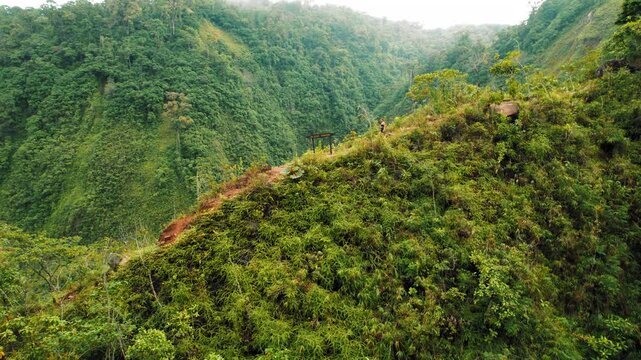 Hiker walking on a lush green ridge overlooking deep valleys in Costa Rica