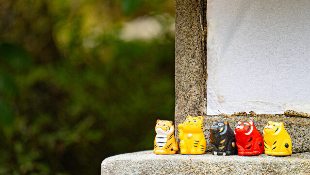Colorful tiger zodiac figurines lined up on a stone ledge