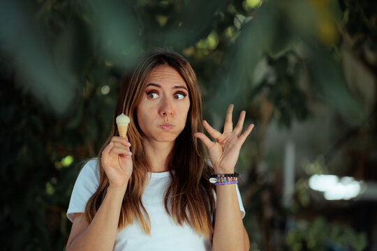 Funny Woman Holding Mini Ice Cream Making Small Gesture. A playful female model holds a tiny dessert showing little scale with fingers