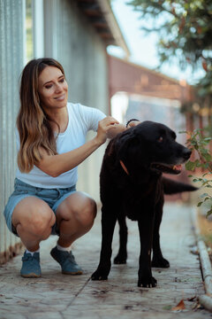 Woman Sneezing From Pet Allergy While Sitting Next To Her Black Dog. Allergic female owner sneezes into tissue near a domestic animal outdoors