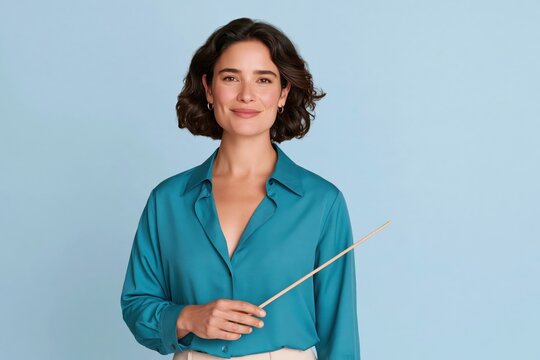 Woman in teal silk shirt holding wooden conductor baton against light blue studio background, confident expression, professional portrait