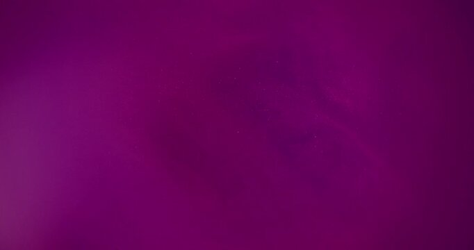 Defocused acrylic paint. Purple pigment water. Blue color underwater glitter shiny particles spreading on abstract art background.