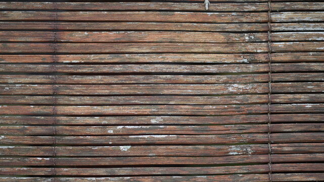 Close-up of weathered brown bamboo blinds texture with horizontal slats and rustic wood grain, vintage wooden curtain background for design projects and architectural backgrounds.