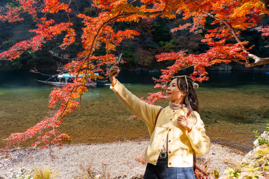 Young happy tourist enjoying the Katsura River at Arashiyama during autumn foliage in Kyoto, Japan