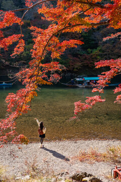 Young happy tourist enjoying the Katsura River at Arashiyama during autumn foliage in Kyoto, Japan