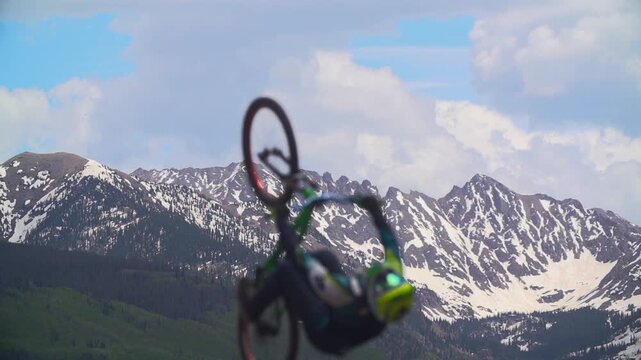 Slow motion shot of BMX rider doing backflip in the snow covered mountains