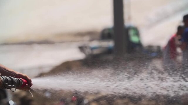 Slow motion shot of man watering down dirt with high power hose