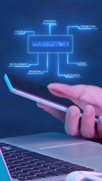 Businessman using smartphone over laptop vertical shot with glowing marketing strategy flowchart mind map. Corporate brand development, promotional campaign planning, and market research concept.
