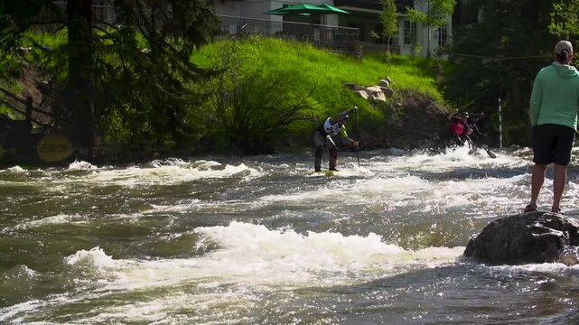 Stand up paddle boarders racing down a river