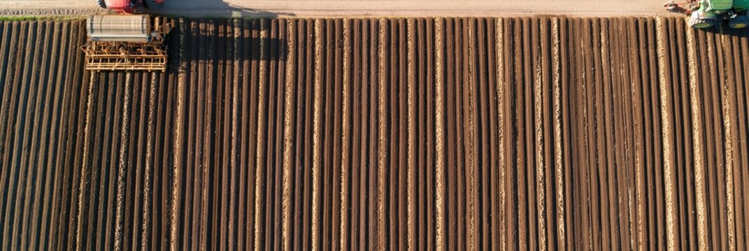 Aerial view of tractor planting crops in neat rows on fertile brown field