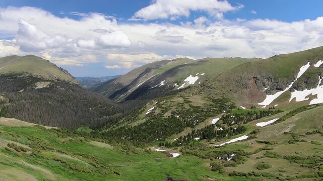 Mountain valley with snow patches and green slopes.