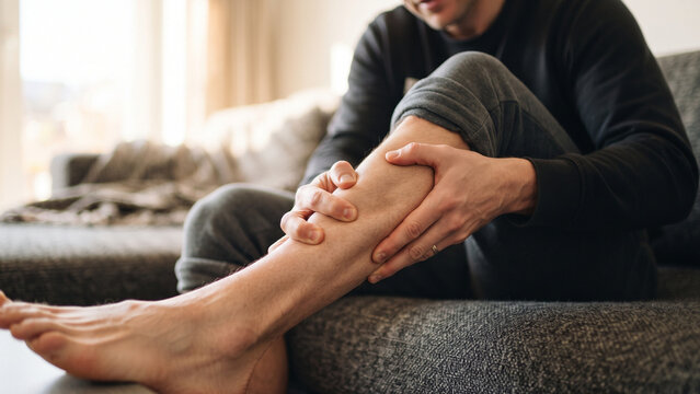 Man suffering from calf muscle cramp or pain at home