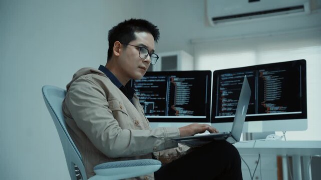 Professional developer programming on a laptop in a modern office, focused on coding and software development