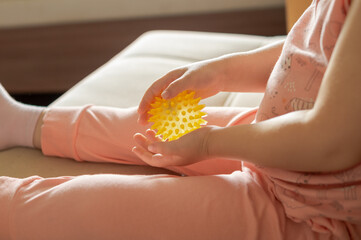 Obraz premium Macro of a child's hands squeezing and roll a yellow spiky massage ball. Concept of sensory therapy, pediatric acupressure, tactile learning, preschool fine motor skills development.