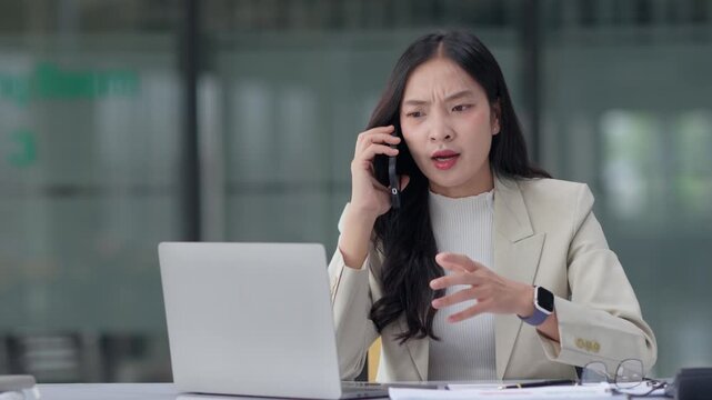 Angry businesswoman arguing on smartphone, having a stressful business conversation in the office