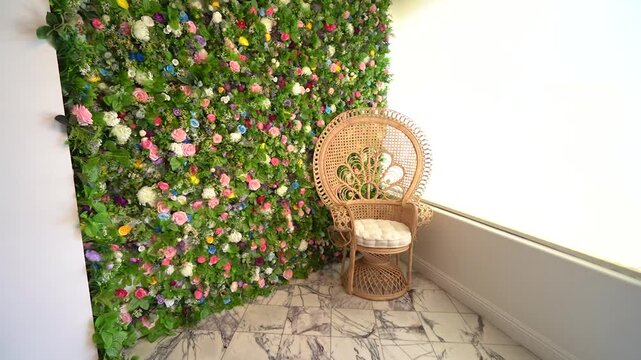 Wicker peacock chair in front of a colourful flower wall