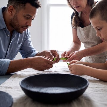 Familie pult gemeinsam frische Erbsen am K&uuml;chentisch