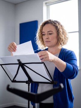 Musikerin sortiert Notenbl&auml;tter am Notenst&auml;nder im Probenraum