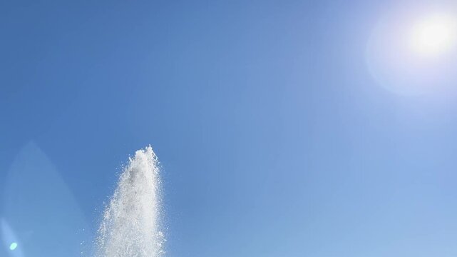 Fountain jet rises into clear blue sky beneath bright summer sun