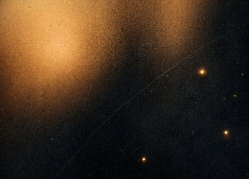 Warm abstract texture presents luminous golden field fading into darkness. Abstract texture includes scattered bright specks, delicate scratch lines, and dramatic low light feel across surface.