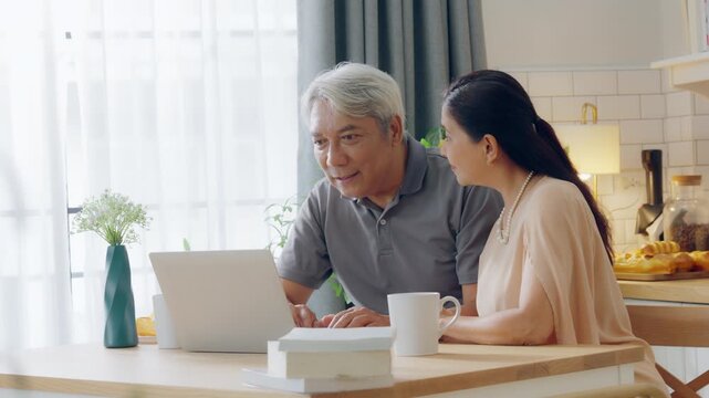 Senior spouses using laptop together sitting on couch at home. Elderly couple, hug and love on sofa with happy marriage, support and conversation of retirement home